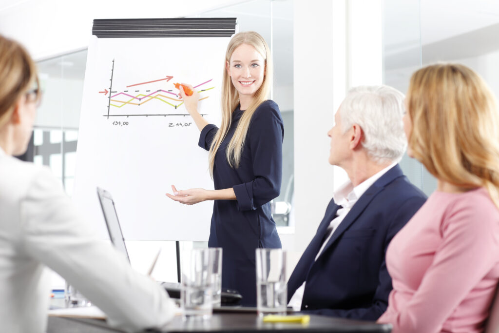 Presenting new project beautiful female business professional standing in front of clipboard and sharing her ideas with her colleagues at business meeting good communication skills